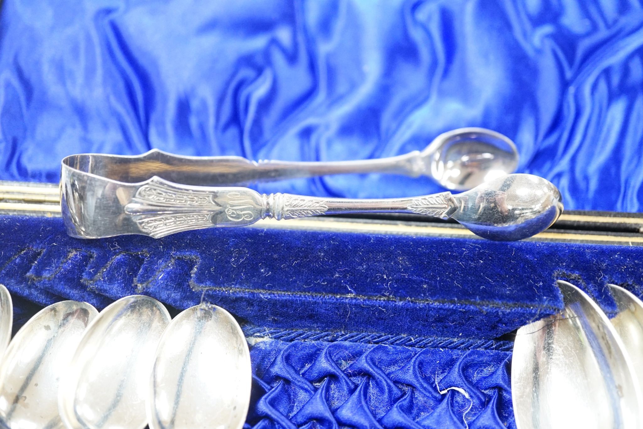 A cased set of six silver bean end coffee spoons, two other sets of six teaspoons and a pair of silver sugar tongs.